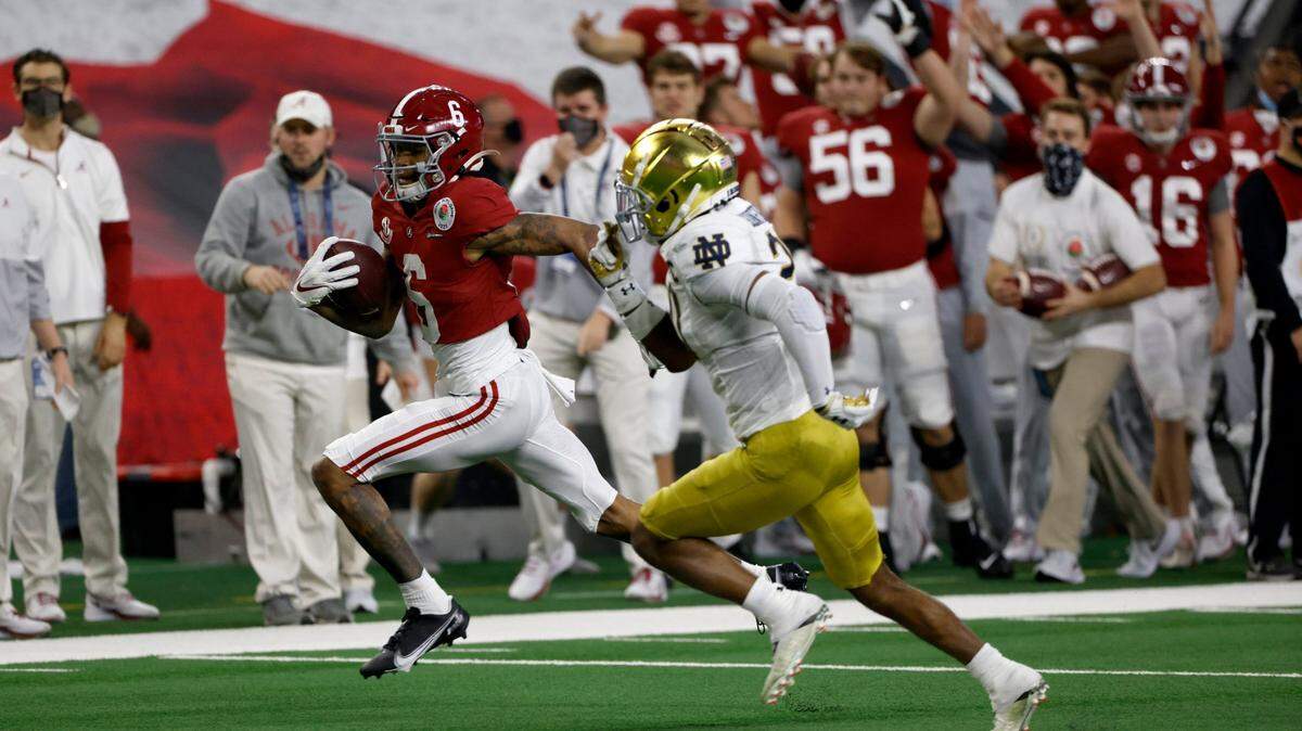 The Alabama sideline erupts in celebration as wide receiver DeVonta Smith (6) sprints to the end zone for a touchdown as Notre Dame safety Shaun Crawford (20) gives chase in the first half of the Rose Bowl NCAA college football game in Arlington, Texas, Friday, Jan. 1, 2021.