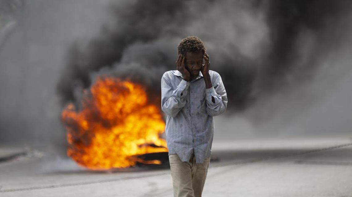 In October 2022, a man walks past a burning barricade during a protest over the death of journalist Romelo Vilsaint, in Port-au-Prince.