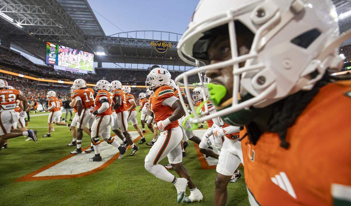 The Miami Hurricanes run off the field after warming up before playing against the Notre Dame Fighting Irish in their NCAA football game at Hard Rock Stadium on Sunday, Aug. 31, 2025, in Miami Gardens, Fla.