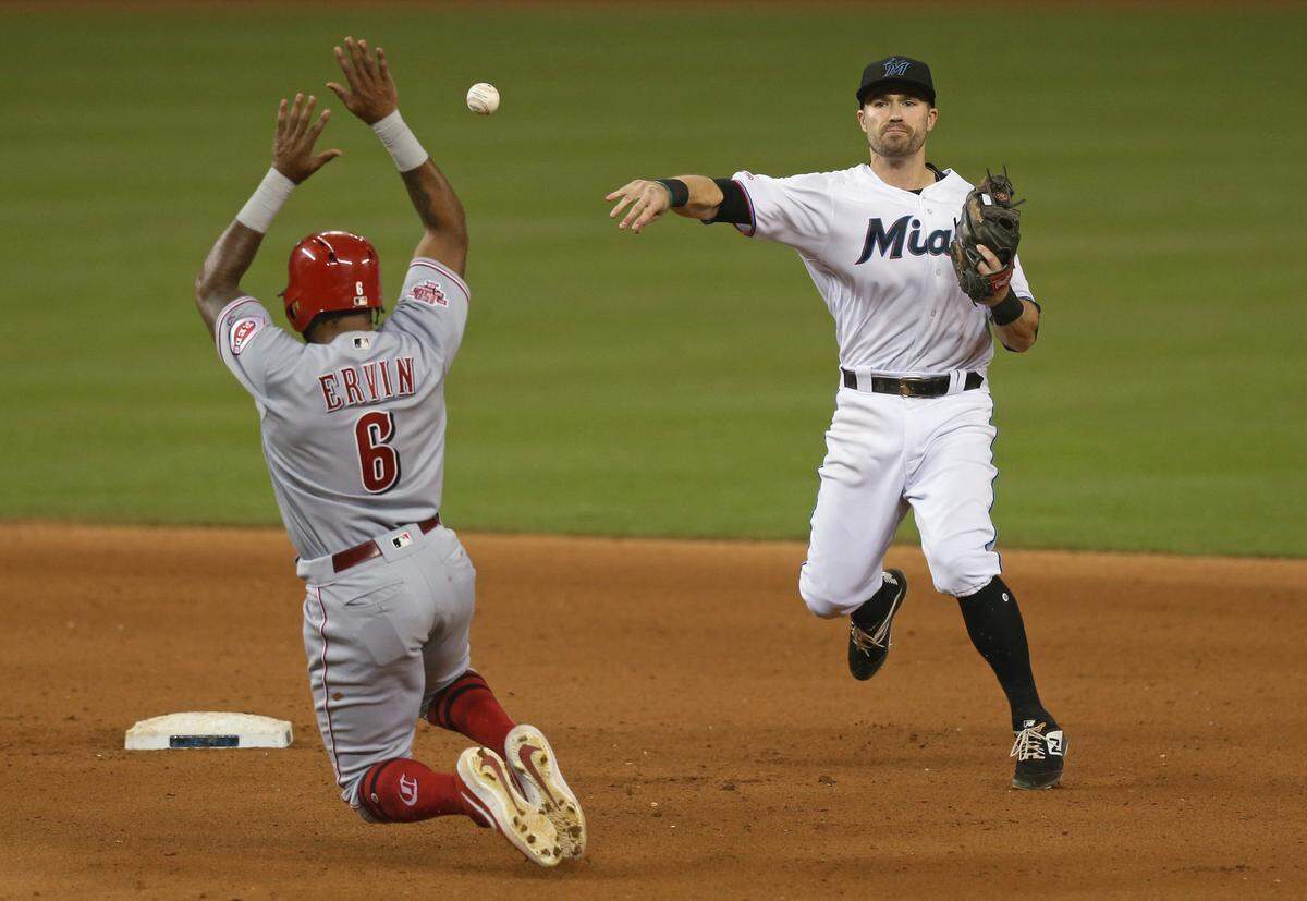 Cincinnati Reds left fielder Phillip Ervin (6) slides as Miami Marlins shortstop Jon Berti (55) throws to first base to complete the double play during the tenth inning of a Major League Baseball game at Marlins Park in Miami on Thursday, August 29, 2019.