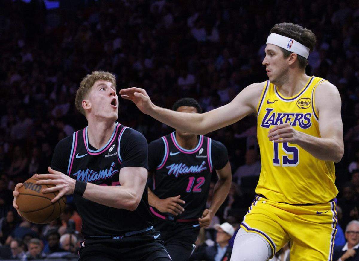 Miami Heat guard Kasparas Jakucionis (25) looks at the basket around Los Angeles Lakers guard Austin Reaves (15) during the first half of a game on March 19, 2026, at Kaseya Center in Miami.