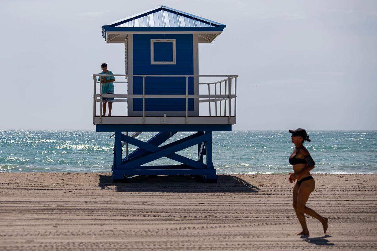A runner makes her way down Hollywood Beach on Tuesday, the first day beaches reopened in Broward County after more than two months of restrictions due to COVID-19.