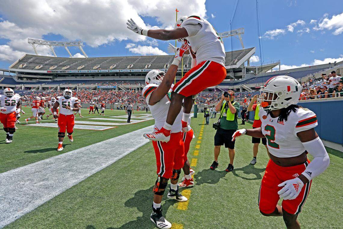 Miami Hurricanes running back DeeJay Dallas (13) is lifted by Miami Hurricanes offensive lineman Kai-Leon Herbert (57) after Dallas scores in the first quarter during the Miami Hurricanes spring game at Camping World Stadium in Orlando on Saturday, April 20, 2019.