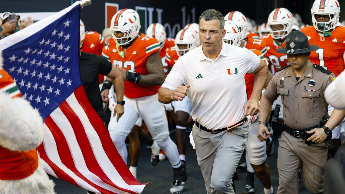 Miami Hurricanes head coach Mario Cristobal runs out to the field with players for the start of an NCAA football game against the NC State Wolfpack at Hard Rock Stadium in Miami Gardens, Florida, on Saturday, November 15, 2025.