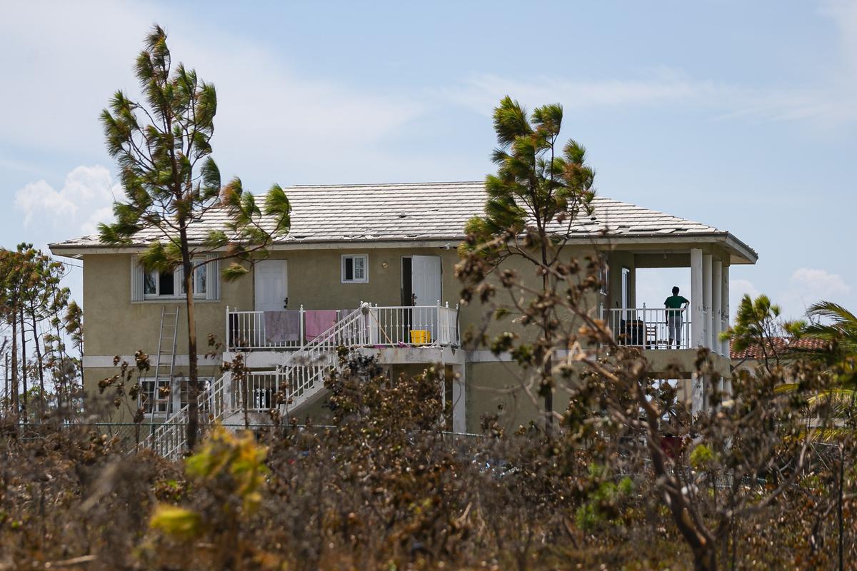 A woman looks out from the balcony of her home in Freeport, Bahamas on Friday, September 6, 2019. Thousands of Bahamians are heading to Freeport Harbor trying to escape Hurricane Dorian’s devastation.