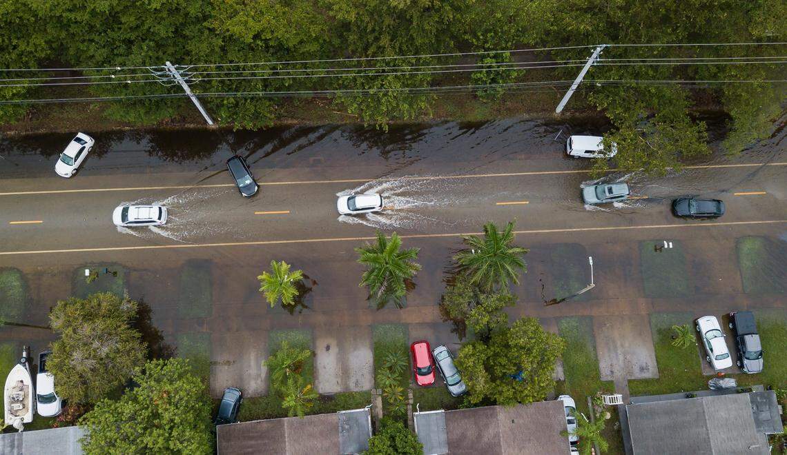Drivers make their way past abandoned cars sitting on a flooded North 14th Avenue on Thursday, June 13, 2024, in Hollywood, Fla. Residents in Hollywood woke up to flooded streets and debris after Wednesday’s storm left their community inundated by heavy rain.