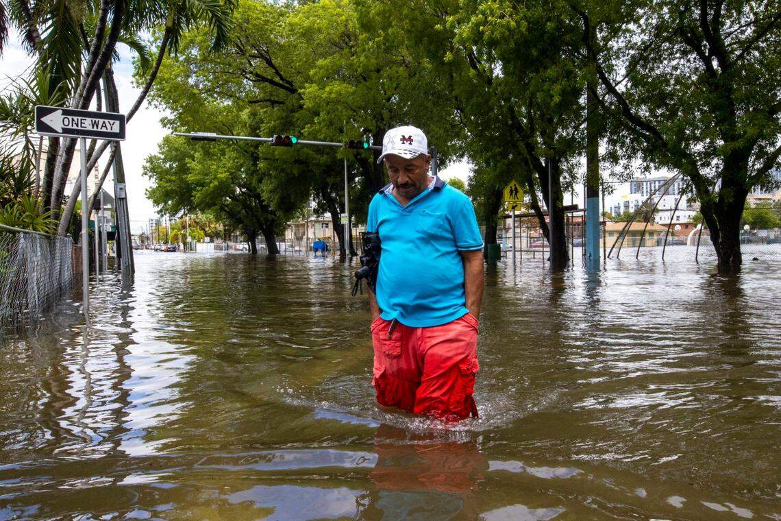 A man crosses the flooded intersection near Southwest Fourth Street and Eighth Avenue in the Little Havana neighborhood of Miami, Florida, on Saturday, June 4, 2022.