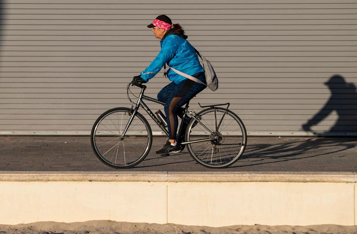 A cyclist makes her way down the Hollywood Beach Broadwalk as temperatures dip into the mid 40s on Saturday, Jan. 14, 2023, in Hollywood, Fla.