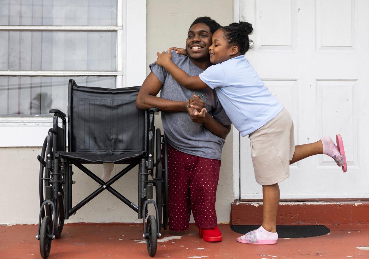 Shanice Wilson, 5, hugs her brother, Elijah Solomon, 19, outside of their home in Miami Gardens, Fla. Solomon.