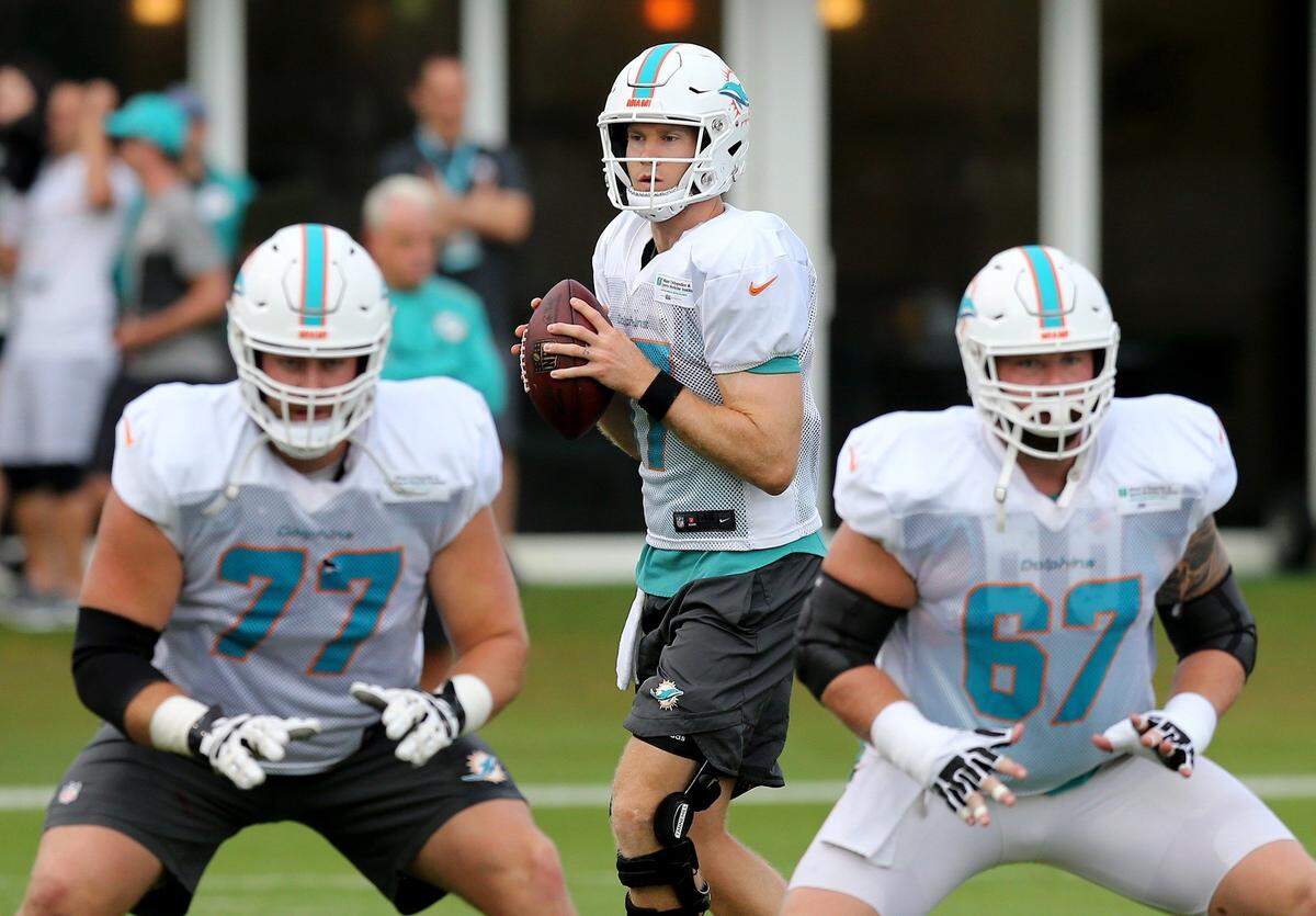 Miami Dolphins quarterback Ryan Tannehill (17) looks down field behind offensive lineman Jesse Davis (77) and Daniel Kilgore during a drill at the Miami Dolphins facility in Davie, Florida, July 29, 2018. 