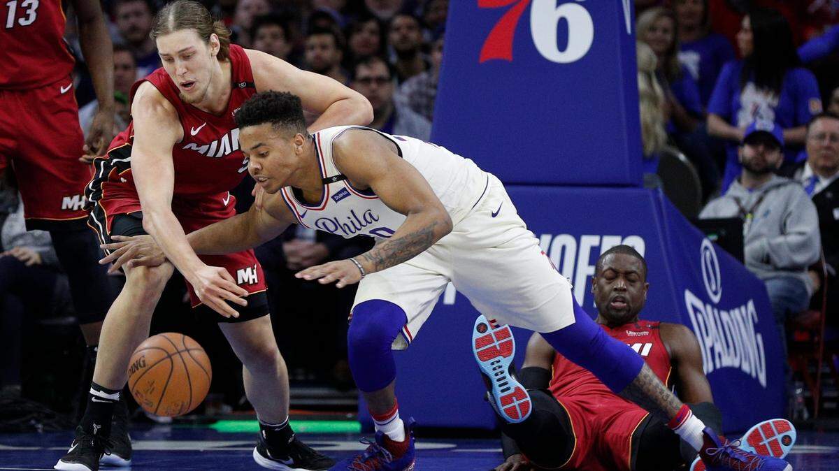 Philadelphia 76ers' Markelle Fultz, center, and Miami Heat's Kelly Olynyk, left, go after the ball as Dwyane Wade, right, falls backwards during the first half in Game 2 of a first-round NBA basketball playoff series, Mon., April 16, 2018, in Philadelphia.
