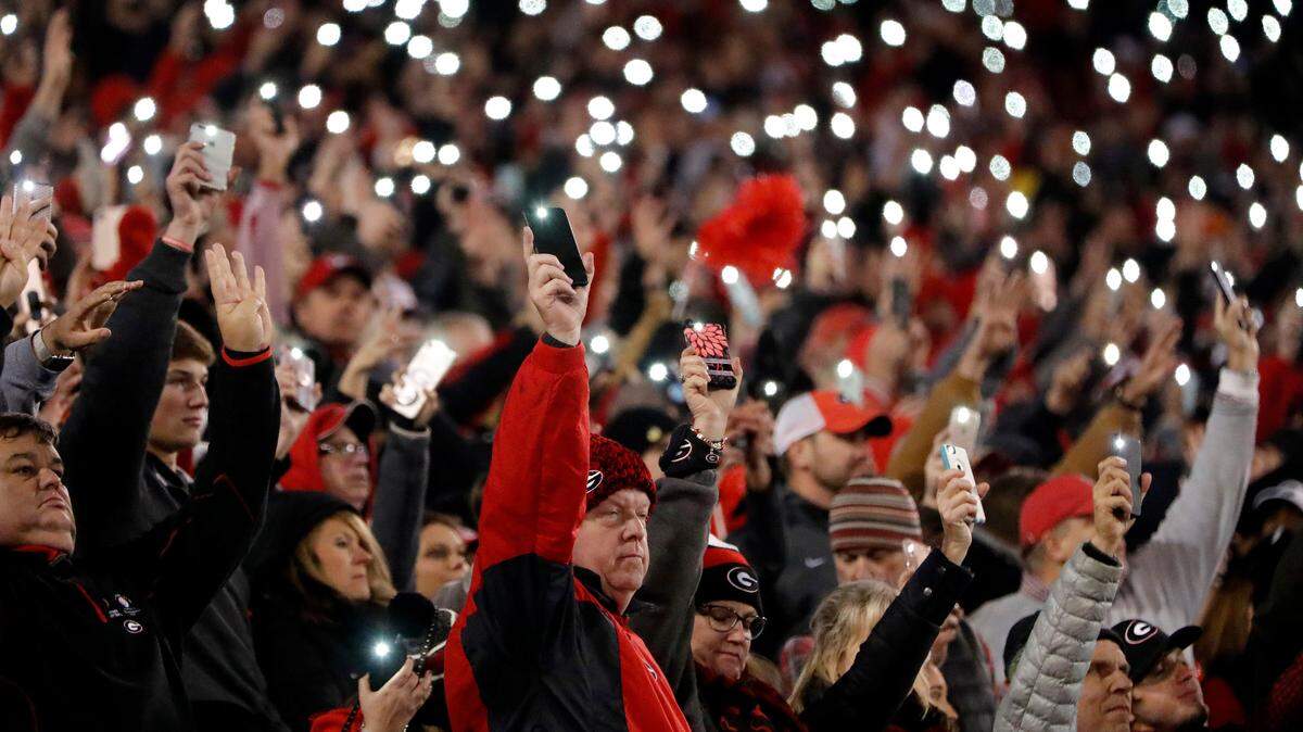 Fans watching the second half of an NCAA college football game between Auburn and Georgia use their cell phones to illuminate Sanford Stadium during a timeout Saturday, Nov. 10, 2018, in Athens, Ga.