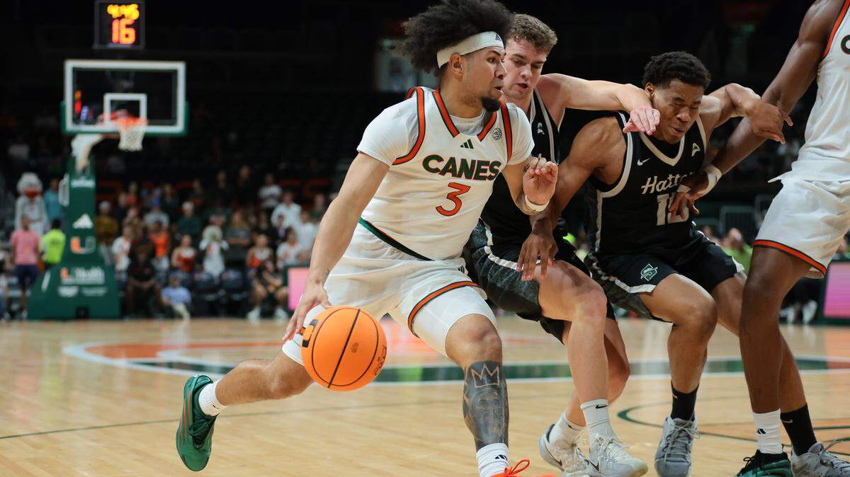 Miami Hurricanes guard Tre Donaldson (3) drives to the basket against Stetson Hatters guard Ethan Copeland (1) and guard J.R. Leonard (15) during the first half at Watsco Center in Coral Gables, Florida, on Monday, Nov. 10, 2025.