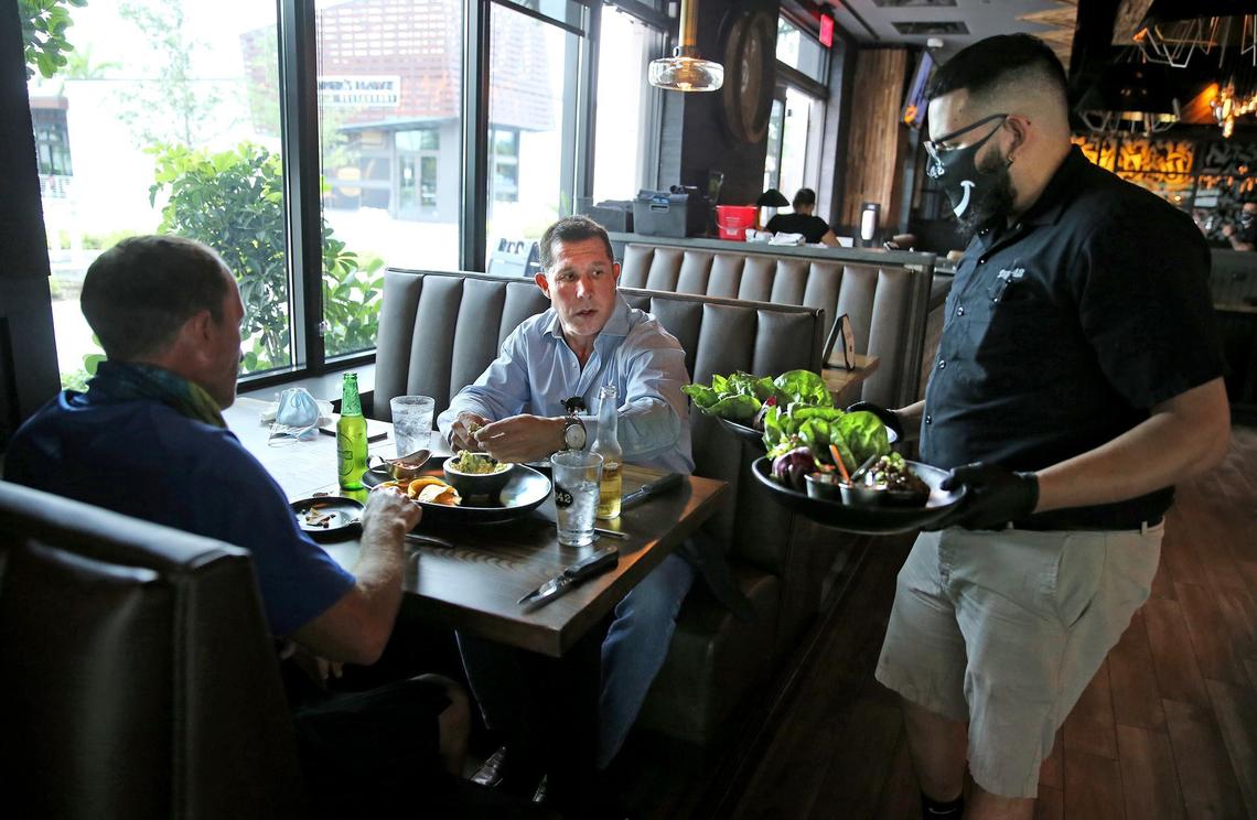 DJ Darcello is the first to order food at Tap42 Doral at City Place after the coronavirus closed the restaurant industry and other businesses, May 18, 2020. Today the first day restaurants could open at 50 percent capacity.
