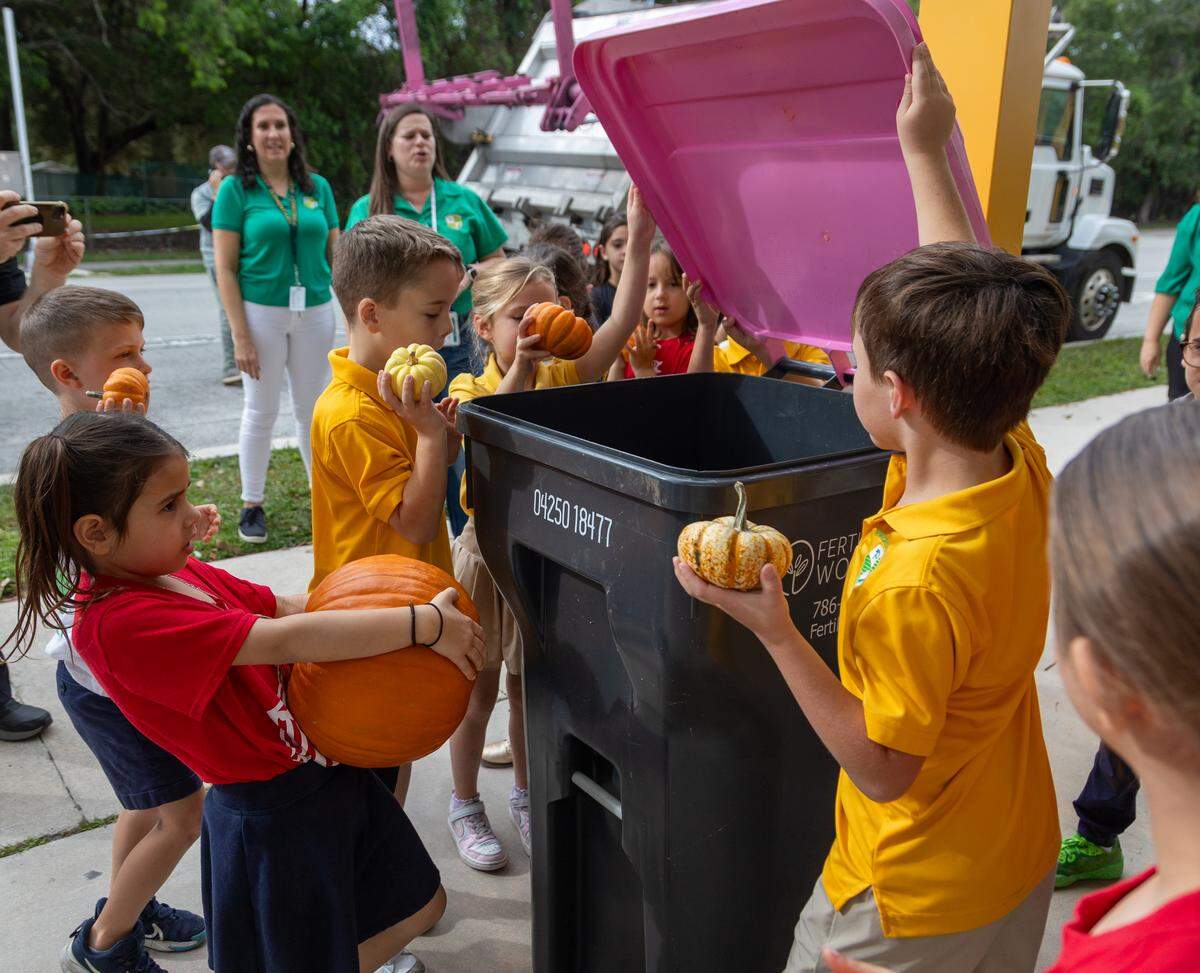 Students at Pinecrest Elementary School put pumpkins into a compost bin outside of their school.