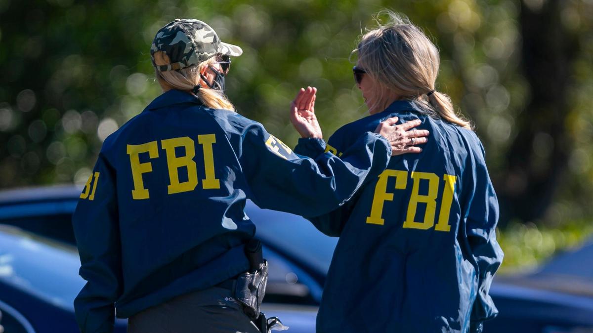 An FBI agent is consoled near the Broward County Office of Medical Examiner and Trauma Services in Fort Lauderdale, Florida on Tuesday, February 2, 2021. Two FBI agents were shot and killed and others injured while serving a warrant at a Sunrise home near Nob Hill Road and Northwest 44th Street.