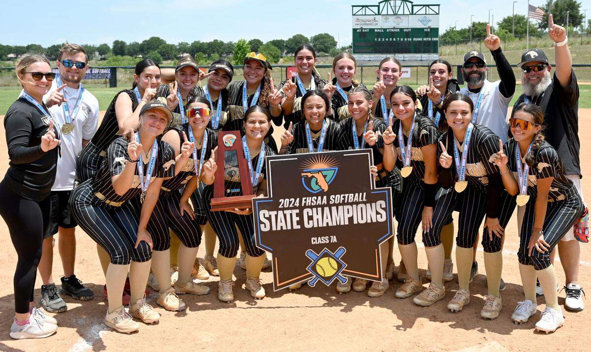 Western softball players gather around the Class 7A softball state championship trophy after winning the second title in program history at the FHSAA Finals on Saturday at Legends Way Ball Fields in Clermont, Fla.