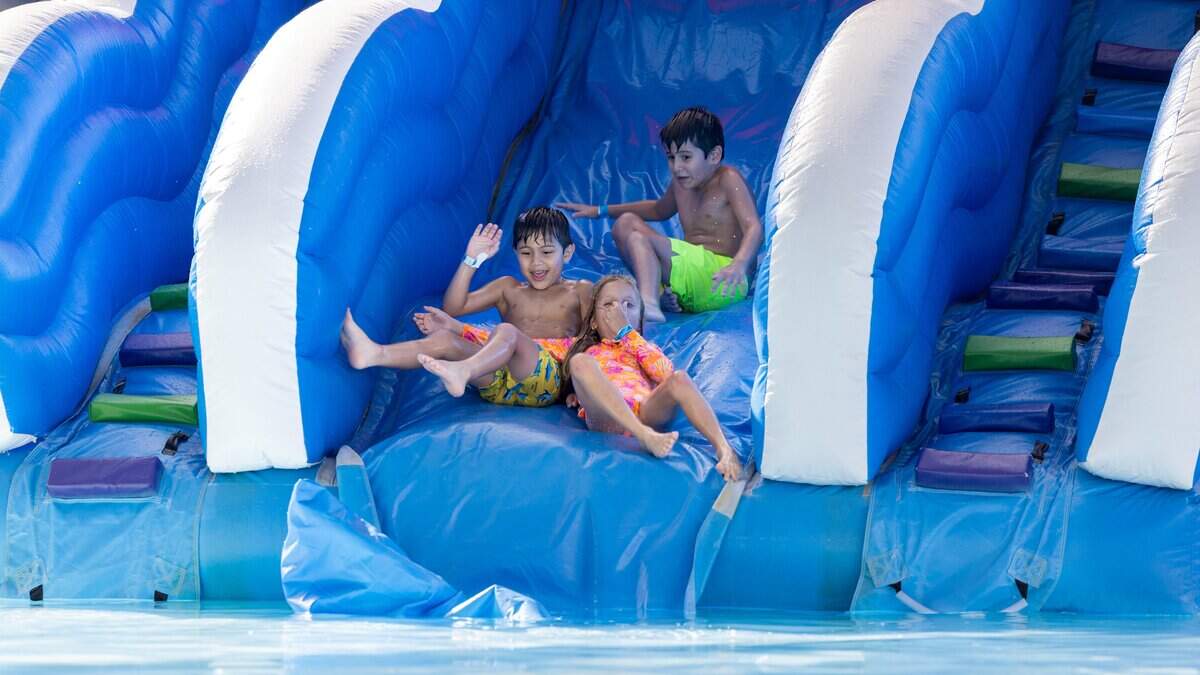 Brothers Adrian Moy, 6 (bottom left), and Alessandro Moy, 7, along with Aitana Rodrigues (bottom right), 7, slide into the water at By Brothers Family Park in the Redland area of Miami, Fla. on Friday, May 29, 2026.