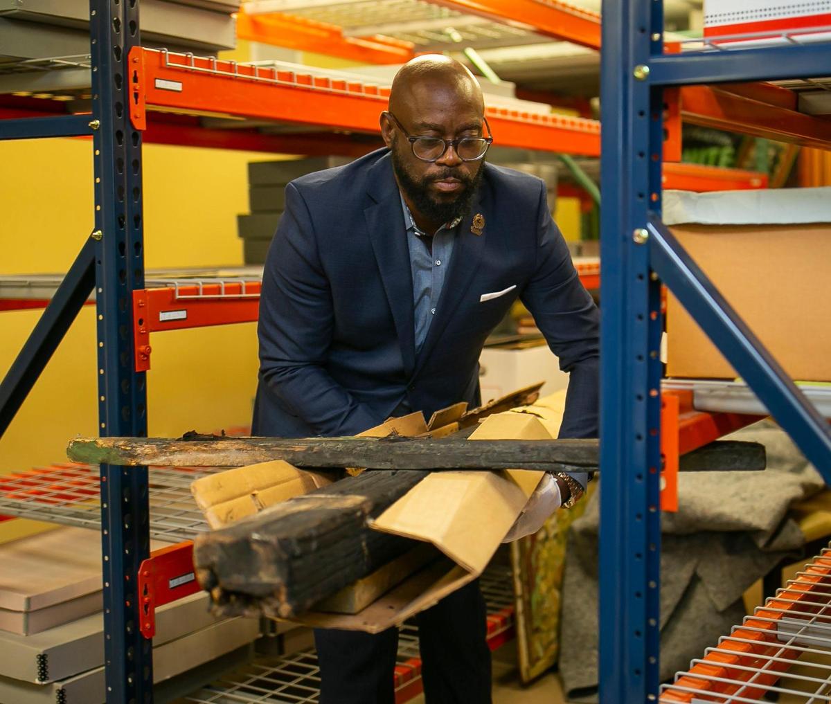 Timothy Barber, executive director of the Black Archives History and Research Foundation of South Florida, handles a cross burned by the Ku Klux Klan in 1949. The cross came from a Catholic church in Miami Shores after a Black priest was assigned to the church, Barber said. Barber, who has led the Archives since 2009, is stepping down to become director of Florida Agricultural and Mechanical University’s Meek-Eaton Black Archives Research Center and Museum, whose work encompasses the southeastern U.S.