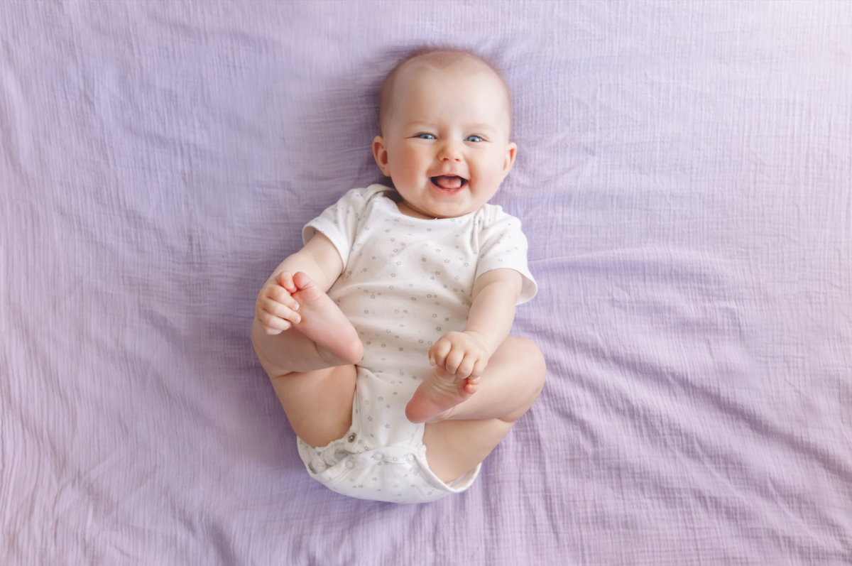 happy baby laying on purple sheets