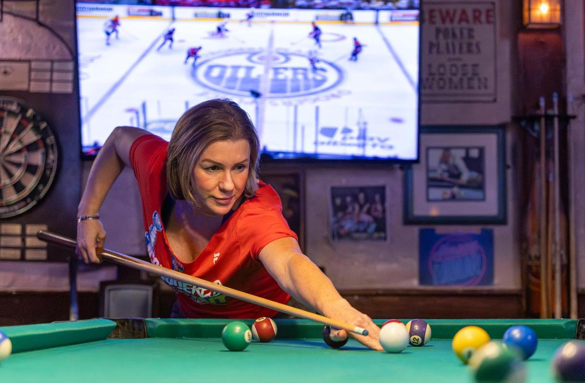 Florida Panthers fan Michelle Zymet plays pool as she watches her team play against the Edmonton Oilers in Game 2 of the NHL Stanley Cup Final at the Inn Field Bar & Grill on Friday, June 6, 2025, in Sunrise, Fla.