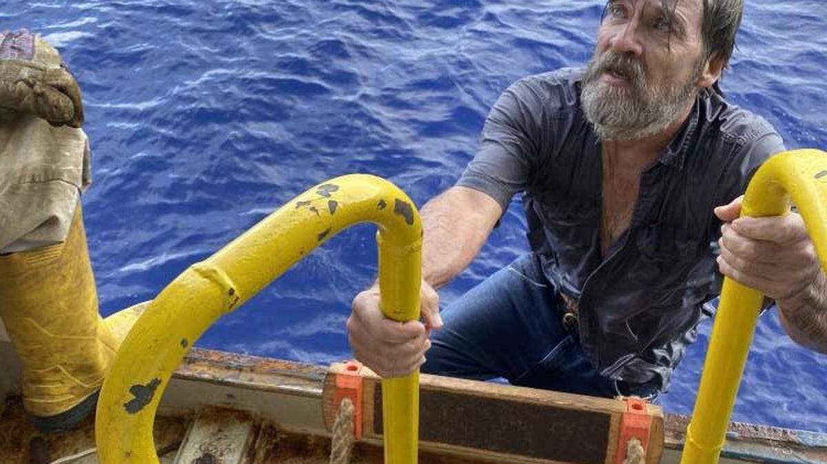 Stuart Bee climbs a ladder to board the Angeles, a 225-foot cargo ship whose crew rescued Bee from his sinking boat Sunday, Nov. 29, 2020. Bee had been lost at sea for three days.