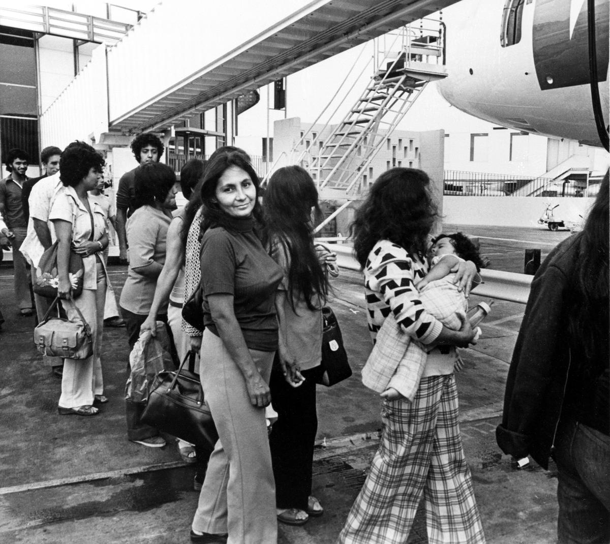 Mexican migrants, among them a woman carrying a baby, are boarding a plane in Los Angeles, Calif., as they are being deported back to their native Mexico, July 27, 1976.