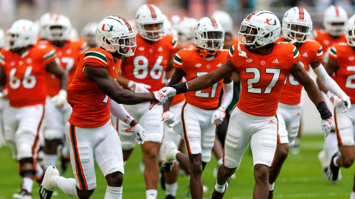 Miami Hurricanes safety Brian Balom (27) and linebacker Avery Huff (9) take the field with teammates before the start of an ACC conference football game against North Carolina Tar Heels at Hard Rock Stadium on Saturday, October 8, 2022 in Miami Gardens, Florida..