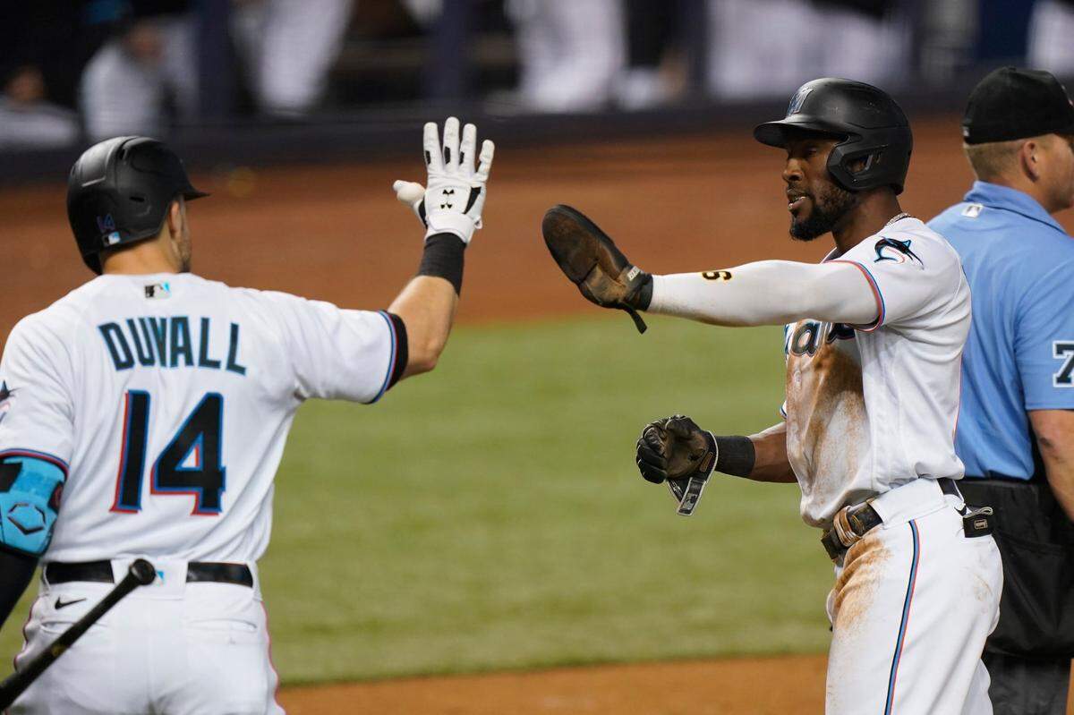 Miami Marlins’ Starling Marte, second from right, is congratulated by Adam Duvall (14) after scoring on a single by Garrett Cooper during the third inning of a baseball game against the Los Angeles Dodgers, Monday, July 5, 2021, in Miami.