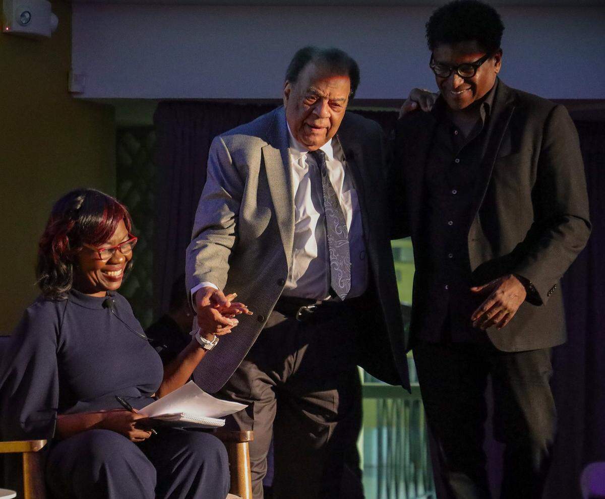 Miami Herald senior reporter Jacqueline Charles, left, extends her hand in aid as Andrew Young is helped on stage by Curb Gardner, right, on Sunday, Feb. 19, 2023. Charles interviewed Young during the Black History Month event at the Historic Hampton House in Miami, Florida.