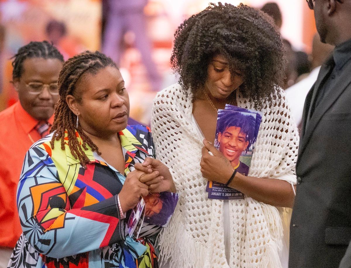 Shibbon Winelle clutches a photograph of her son Bryce Jaden-Lee Zane Gowdy during a memorial service for the senior football player at Deerfield Beach High School on Saturday, January 11, 2020.