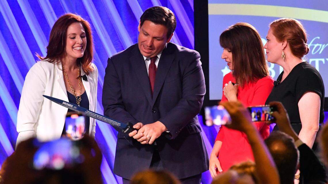 Florida Governor Ron Desantis, center, is presented “The Sword of Liberty” by Moms for Liberty co-founders Tiffany Justice, left, Tina Descovich, second from the right, and executive director of program outreach Marie Rogerson, far right, during the first Moms for Liberty National Summit on Thursday, July 15, 2022, in Tampa.