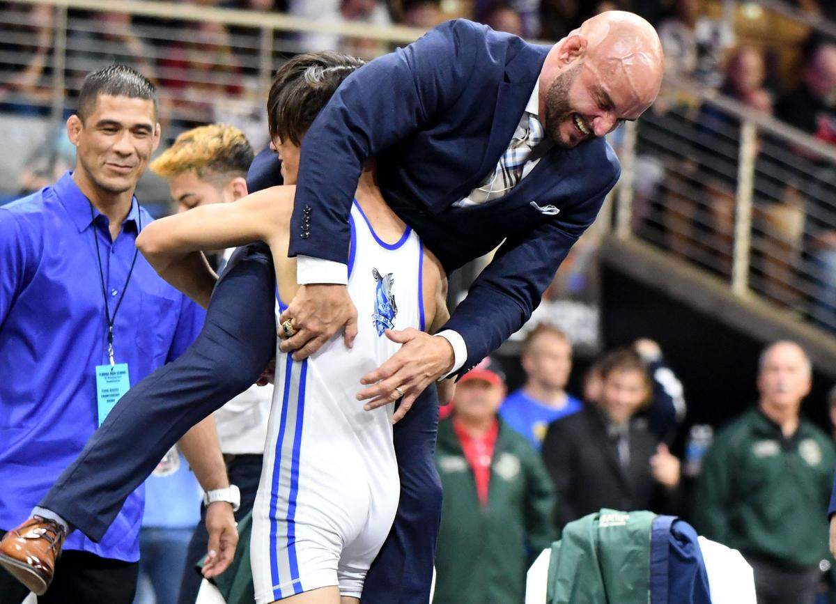 South Dade’s Bryan Morales picks up head coach Victor Balmeceda after winning the Class 3A 106-pound wrestling state championship on Saturday at Silver Spurs Arena in Kissimmee.