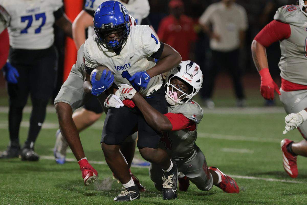 Chaminade-Madonna Lions linebacker Bryant Julius (4) tackles Trinity Christian Academy running back Micah Anderson (1) during the first half of a Class 1A football state semifinal game at Chaminade-Madonna College Preparatory on Friday, Dec. 5, 2025 in Hollywood, Fla.