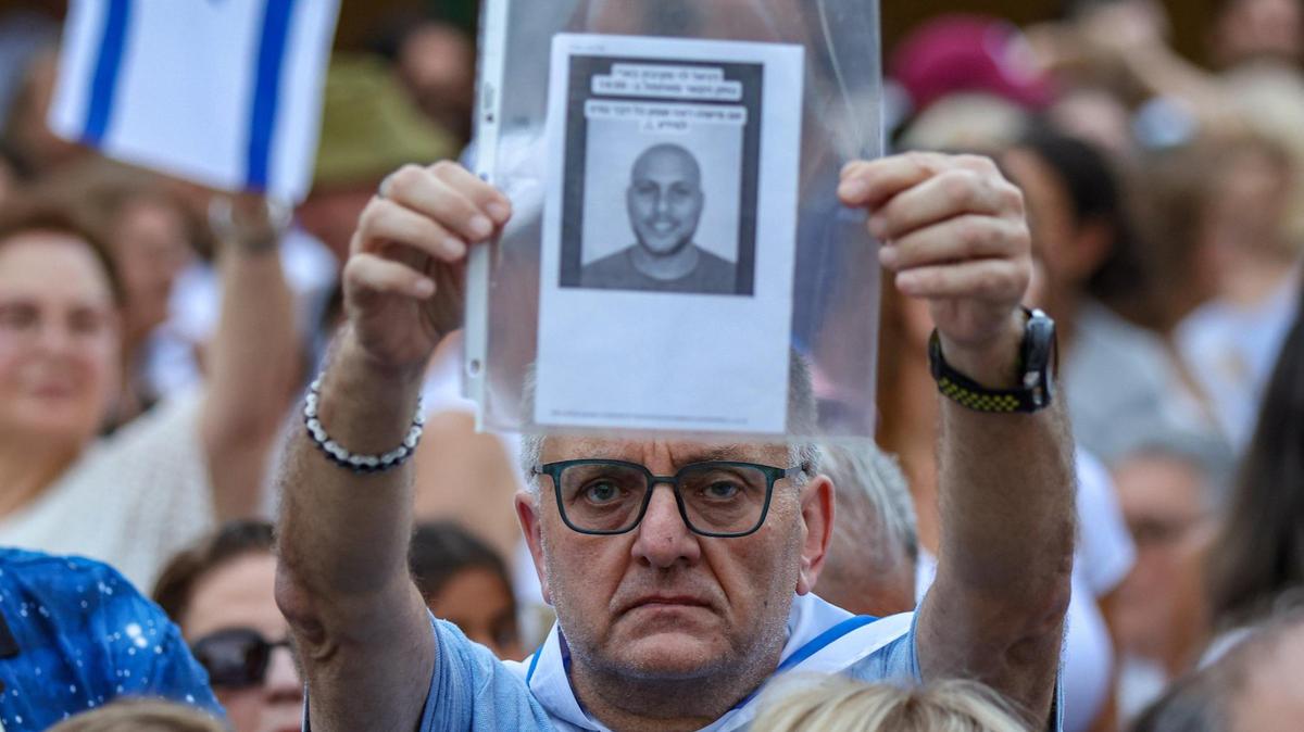 A man holds a photo of a missing relative as attendees wave flags at a Miami, Florida, shopping center to support Israel in its war against Hamas on Monday, Oct. 9, 2023.