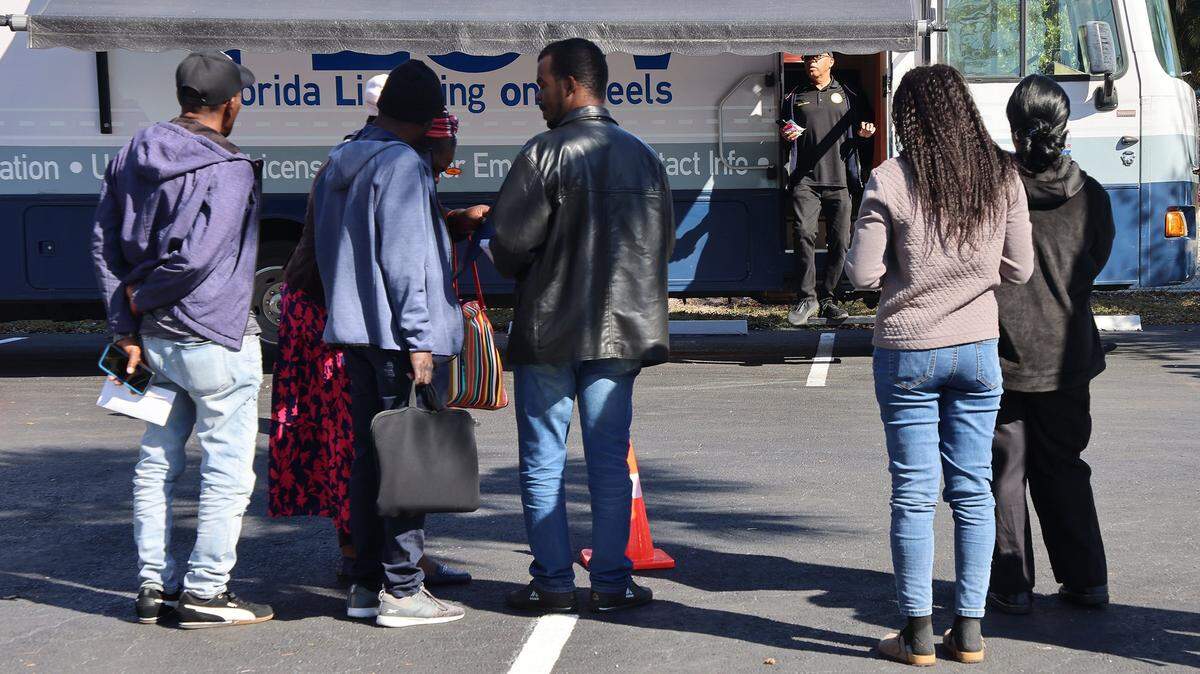 A group waits for their numbers to be called after arriving at the mobile licensing location. A driver's license renewal event for Haiti's TPS recipients was held at Carver Ranches Library in West Park, Florida, on February 26, 2026, to help Haitian immigrants and others update their licenses. NOTE: Please do not lighten faces of licensing renewal applicants. They do not want to be identified.