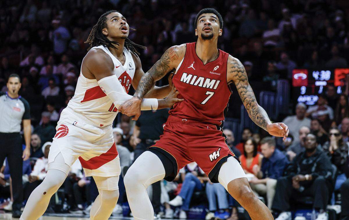 Toronto Raptors forward Collin Murray-Boyles (12) and Miami Heat center Kel'El Ware (7) keep an eye on the rebound during the first half of their NBA basketball game at Kaseya Center in Miami on December 23, 2025.