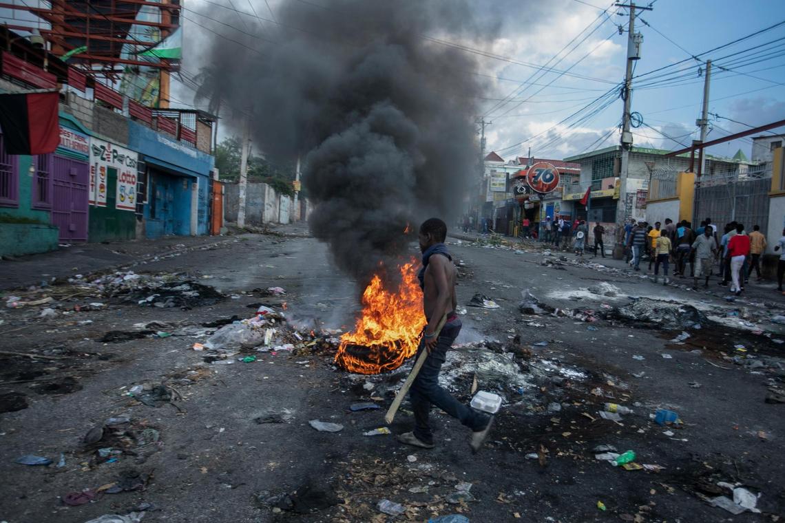 A man walks past burning tires set up by protesters during a protest demanding the resignation of Prime Minister Ariel Henry in the Delmas area of Port-au-Prince, Haiti, Monday, Oct. 10, 2022.