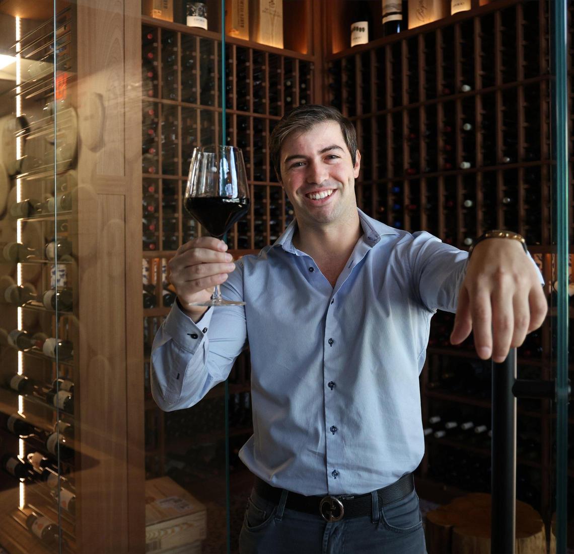 Carlos Silva Jr. holds a glass of wine in the wine room at the new Old Lisbon restaurant in Aventura. The restaurant boasts a large selection of Portuguese wine.