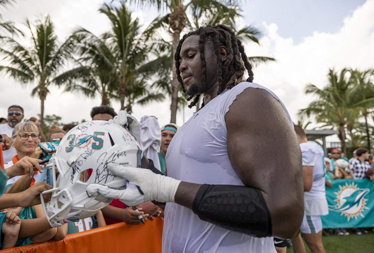 Miami Dolphins offensive tackle Patrick Paul (52) signs autographs for fans after participating in training camp at the Baptist Health Training Complex on Tuesday, July 29, 2025, in Miami Gardens, Fla.