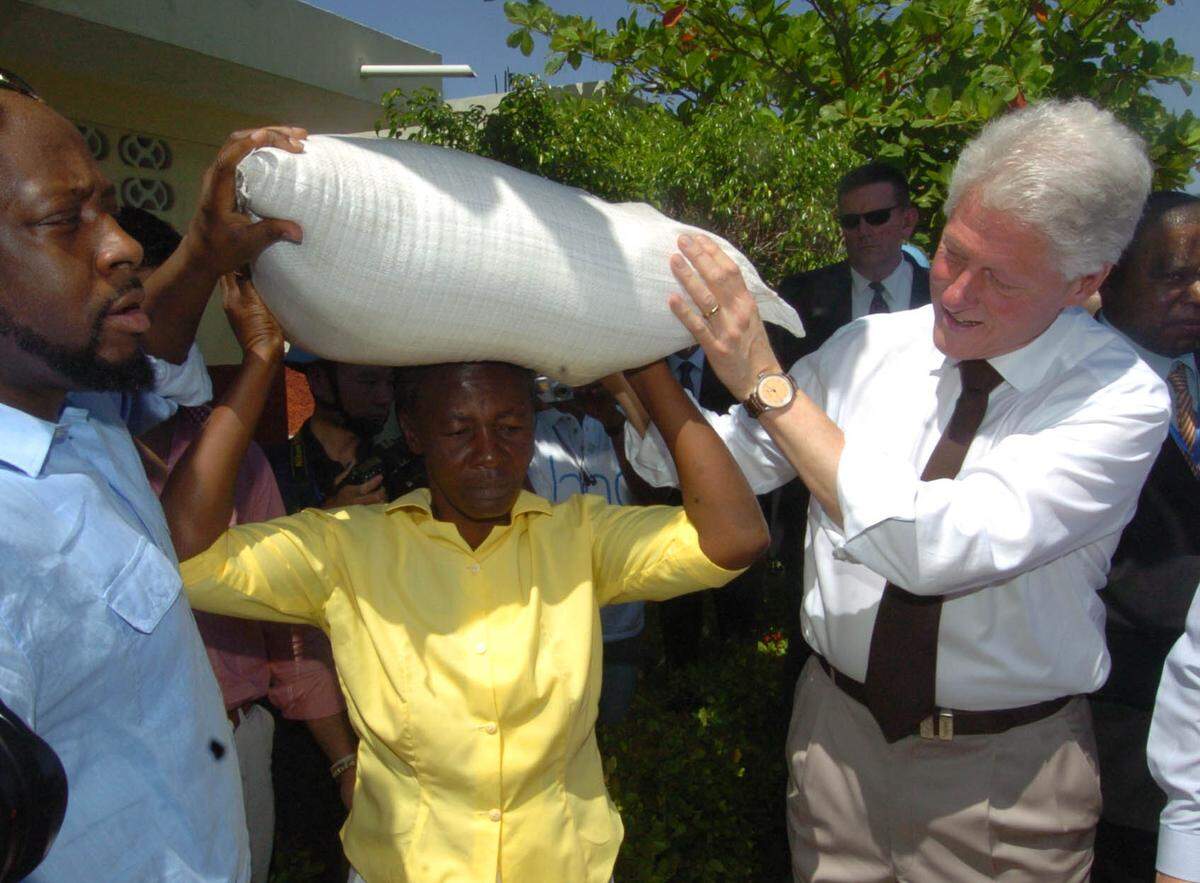 During a September 2009 visit to Cite Soleil in Port-au-Prince with then U.N. Secretary-General Ban Ki-moon, former U.S. President Bill Clinton visited a school feeding program. Here, he helps a women with a bag of rice.