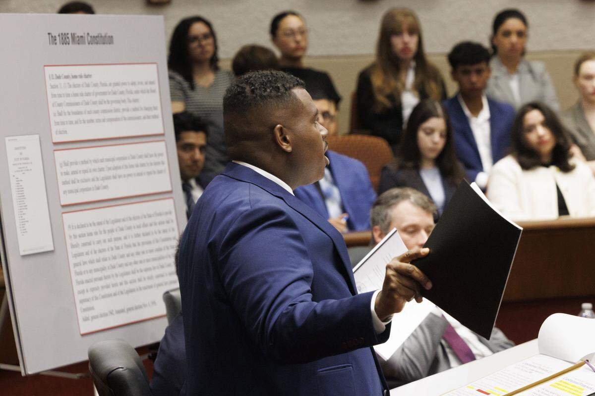 Dwayne Robinson, attorney on the case for the city, holds up two printed versions of the City Charter, which he claims are the same, during a hearing at the Third District Court of Appeal for a case Emilio González brought against the City of Miami on Tuesday, July 29, 2025, in Miami. 