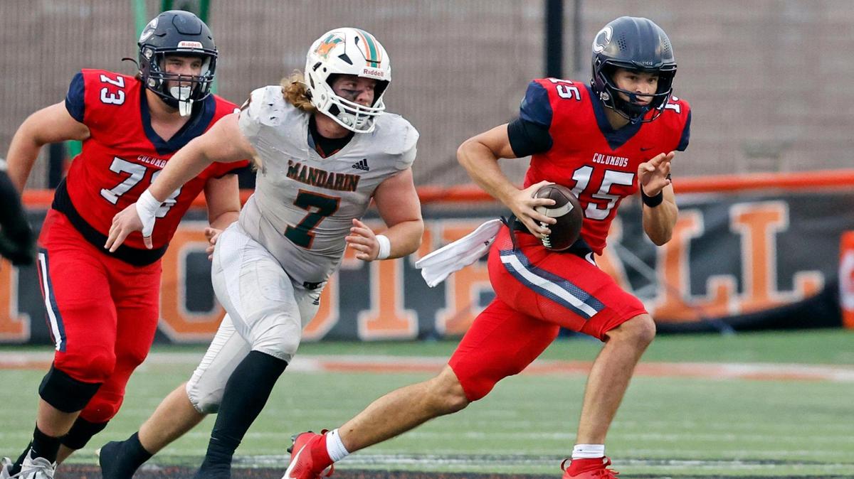 Columbus Explorers quarterback Alberto Mendoza (15) scrambles with the ball as Mandarin Mustangs Jackson Copeland (7) gives chase in the second half of the game of the Class 4M state championship at Bragg Memorial Stadium in Tallahassee, Florida, on Friday, December 8, 2023.