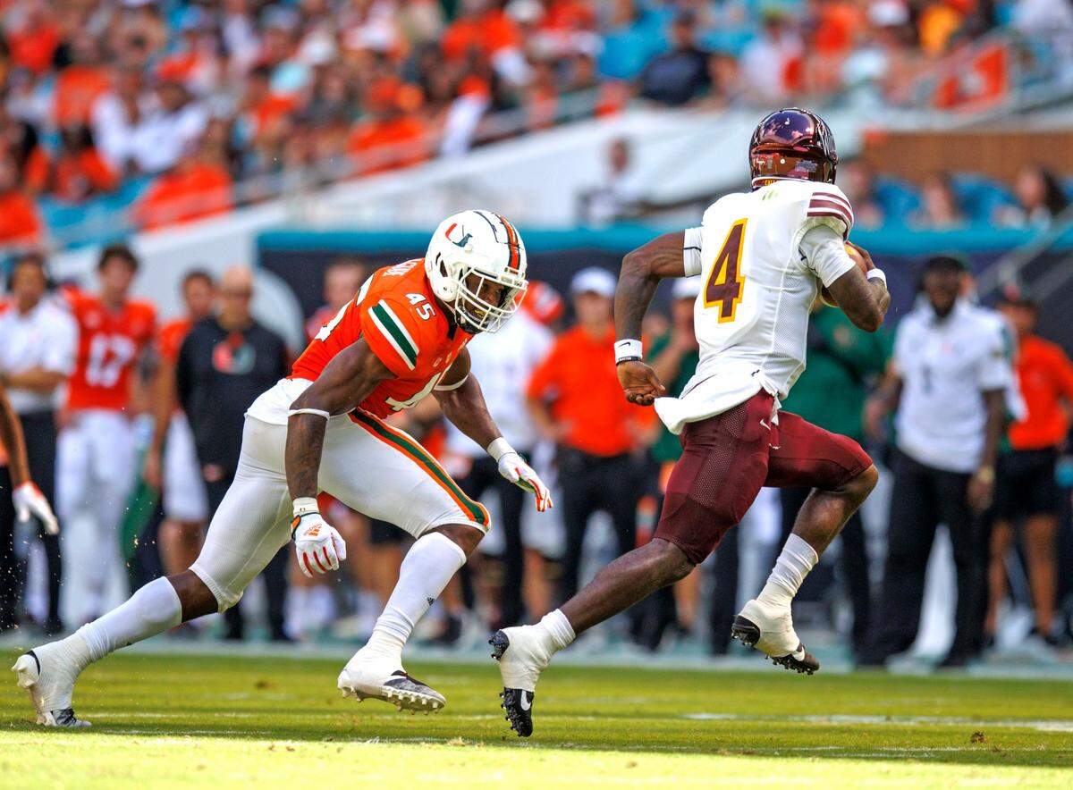 Bethune Cookman Wildcats quarterback Jalon Jones (4) run with the football against the defense from Miami Hurricanes defensive lineman Mitchell Agude (45) during the first quarter of a NCAA non conference football game at Hard Rock Stadium on Saturday, September 3, 2022 in Miami Gardens, Florida.