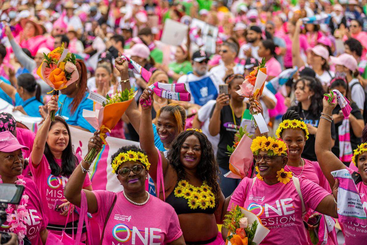 Breast cancer survivors hold flowers and cheer as they attend the Susan G. Komen More Than Pink Walk at Amelia Earhart Park on Saturday, Oct. 8, 2022, in Hialeah, Fla. The event aims to raise awareness and money for breast cancer research.