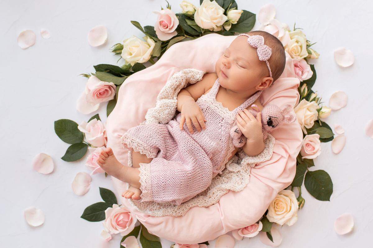baby sleeping on a pile of pink flowers