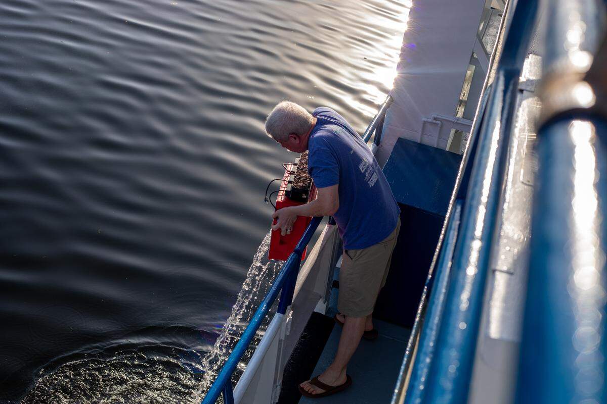 Mark Schick, the senior director of animal operations on the Coral Reef II research vessel owned by Shedd aquarium, dumps water overboard.
