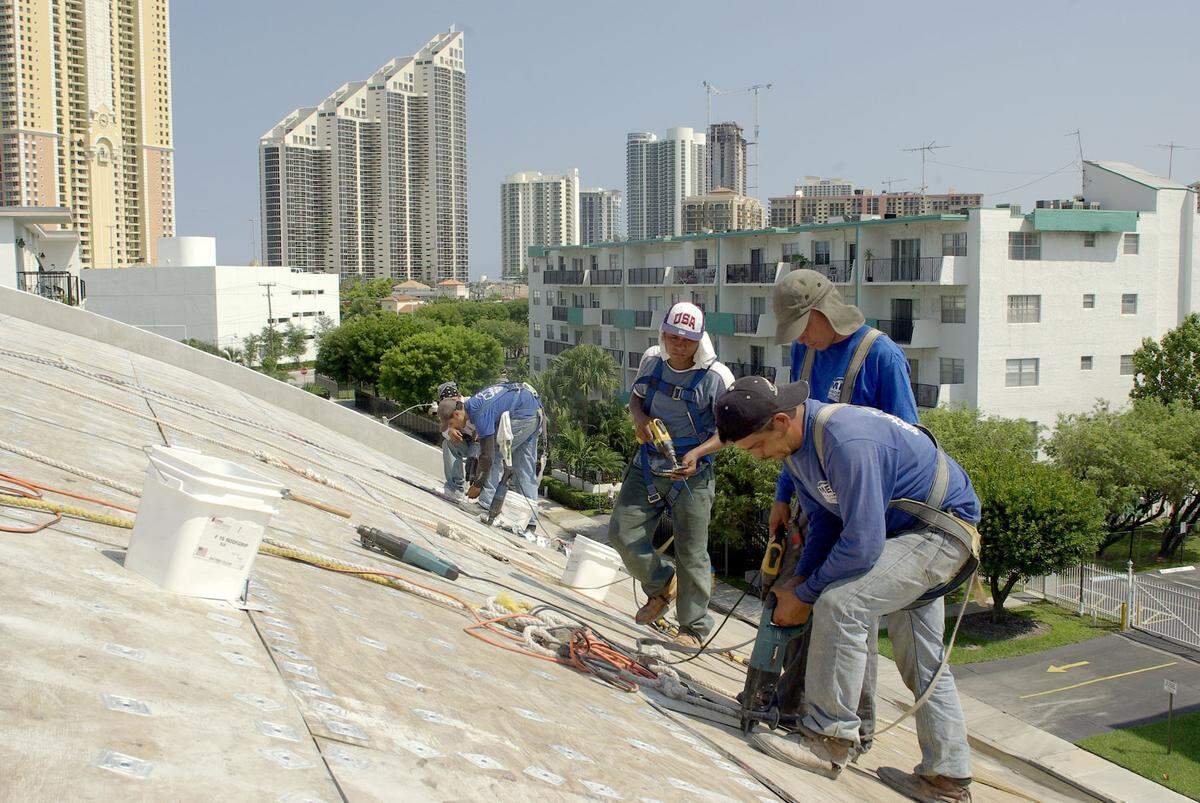 Workers in Sunny Isles Beach sheath a roof.