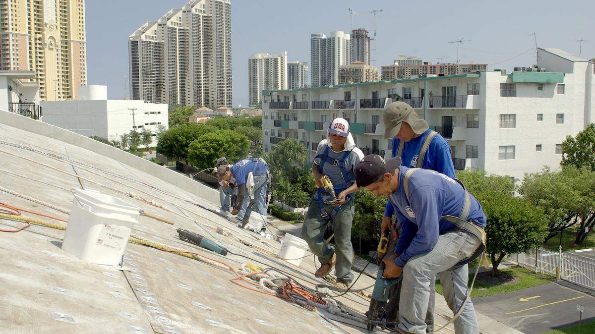 Workers in Sunny Isles Beach sheath a roof.