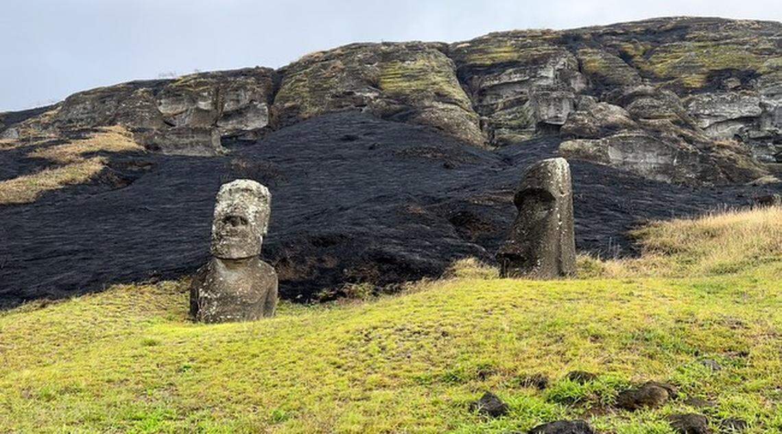 Two Easter Island heads sit on the fire-scorched ground.
